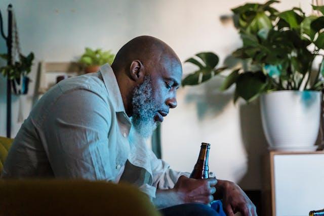 A person sitting alone holding a bottle of beer