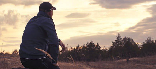 a man sitting in a field thinking about support options for rural veterans in recovery