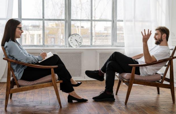 A man in a white shirt talking to a female therapist.