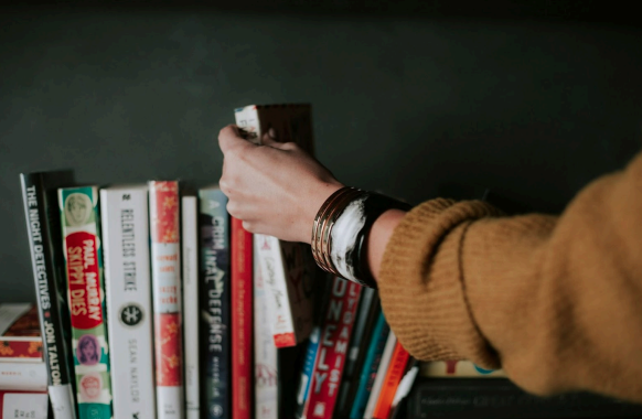 A person taking a book from the shelf.